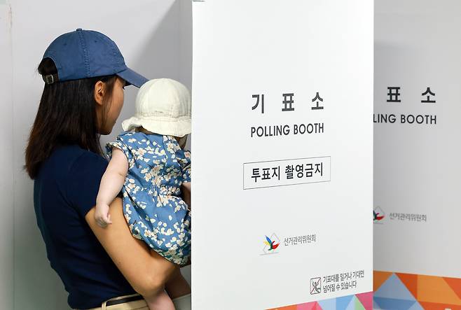 21대 대통령 선거 사전투표 둘째날인 지난달 30일 서울 관악구 낙성대동주민센터에 마련된 낙성대동사전투표소에서 아이를 안은 유권자가 투표하고 있다. 사진은 기사 내용과 직접적 관련 없음. [연합]