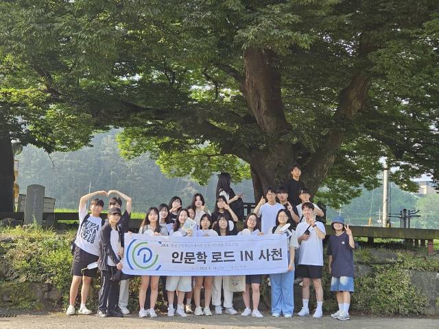학생들이 덕곡마을 당산나무 아래에서 기념촬영을 하고 있다./사천 용남고/