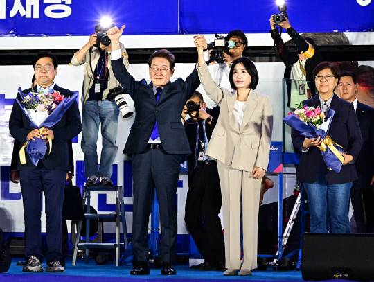 제21대 대통령 당선이 확실시되는 이재명 더불어민주당 대선 후보와 부인 김혜경 여사가 4일 서울 여의도 국회 인근에서 당 주최로 열린 국민개표방송 행사에 참석해 시민들을 향해 인사하고 있다. 연합뉴스