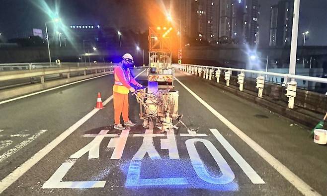 부산 번영로 문현고가 이전 1차로에서 작업자가 융착식 문자 재도색 작업을 하고 있는 모습. 부산시설공단 제공