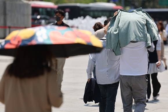 서울 종로구 광화문에서 한 시민이 겉옷으로 햇빛을 가리고 있는 모습. [사진=연합뉴스]