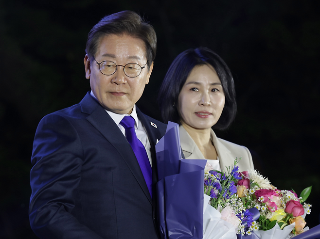President Lee Jae-myung (left) and first lady Kim Hye-kyung receive bouquets during a public vote-count event hosted by the Democratic Party of Korea near the National Assembly in Yeouido, Seoul, Wednesday. (Joint Press Corps)