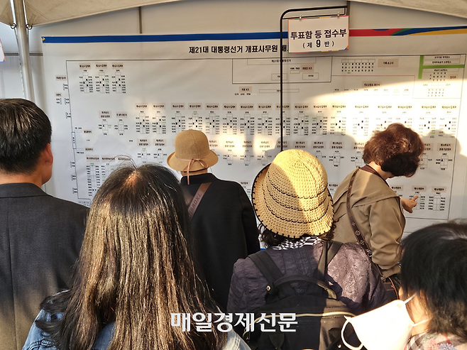 지난 3일 오후 7시께 개표사무원들과 참관인들이 개표소 밖에 부착된 자리표에서 본인의 이름을 찾고 있다. [사진 지혜진 기자]