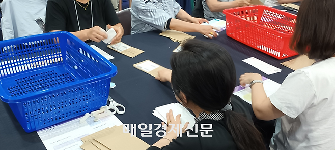 우편투표전담부의 개표사무원들이 회송용봉투에서 투표용지를 빼내고 있다. [사진 지혜진 기자]
