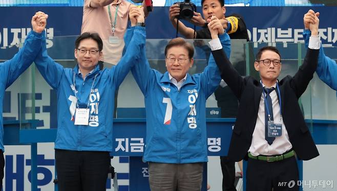 [양산=뉴시스] 조성우 기자 = 이재명 더불어민주당 대선후보가 22일 경남 양산시 양산워터파크공원에서 열린 집중유세에서 김경수(왼쪽) 총괄선대위원장과 찬조연설자의 손을 잡고 시민들을 향해 인사하고 있다. (공동취재) 2025.05.22. photo@newsis.com /사진=조성우