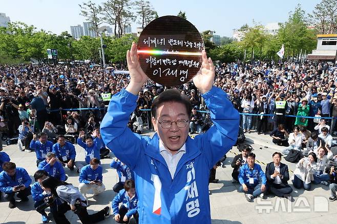 [화성=뉴시스] 조성우 기자 =이재명 대통령이 대선 기간 경기 화성시 동탄 센트럴파크 음악분수중앙광장에서 열린 집중유세에서 '세계1위 반도체 강국도약'이라고 쓴 반도체 웨이퍼를 들어보이고 있다. (공동취재) 2025.05.12. photo@newsis.com