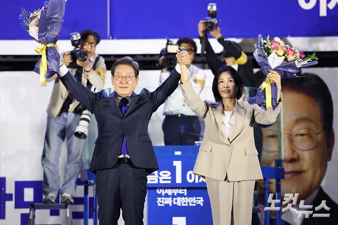 제21대 대통령 당선이 확실시되는 더불어민주당 이재명 대선 후보와 김혜경 여사가 4일 서울 여의도 국회 앞에 마련된 더불어민주당 국민 개표방송 행사에서 꽃다발을 받은 뒤 인사하고 있다. 류영주 기자