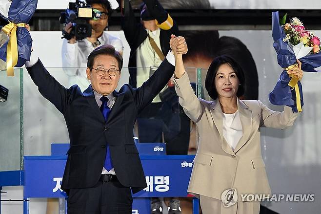 시민들 향해 두 팔 들어 올리는 이재명 후보 내외 (서울=연합뉴스) 김주성 기자 = 제21대 대통령 당선이 확실시되는 더불어민주당 이재명 대선 후보와 부인 김혜경 여사가 4일 서울 여의도 국회 인근에서 당 주최로 열린 국민개표방송 행사에 참석해 꽃다발을 받고서 시민들을 향해 두 팔을 들어 올려 인사하고 있다. 2025.6.4 [공동취재] utzza@yna.co.kr