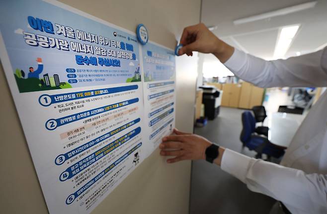 지난 2022년 10월 18일 세종시 정부세종청사 사무실 입구에 공무원이 공공기관 평균 난방 온도 17도 제한 안내문을 부착하고 있다./연합뉴스