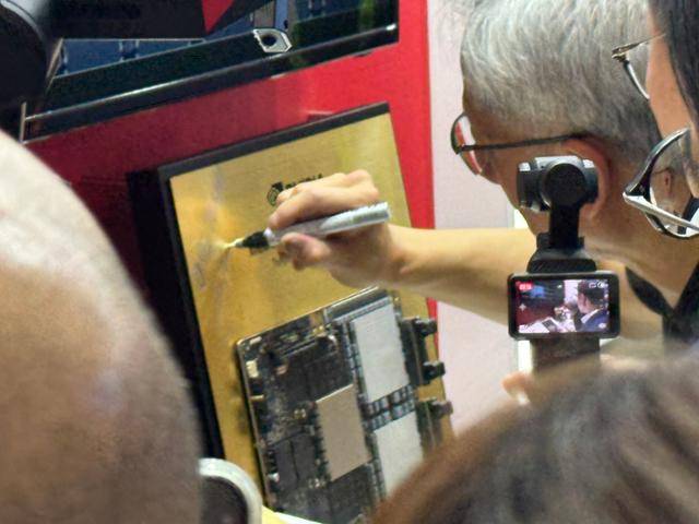 젠슨 황 엔비디아 CEO가 5월 20일 대만+ 타이베이 난강 전시관에서 개최된 '컴퓨텍스 2025'에서 SK하이닉스 부스를 찾아 전시된 HBM에 사인하고 있다. 타이베이=연합뉴스