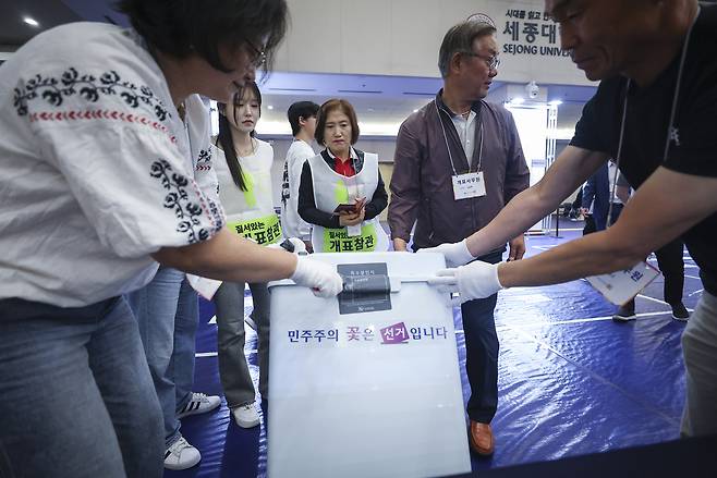 제21대 대통령 선거일인 3일 서울 광진구 세종대학교 컨벤션센터에 설치된 개표소에서 개표사무원들이 관내 투표소에서 이송된 투표함을 옮겨 개표하기 위해 특수 봉인지를 떼어내고 있다. [연합]