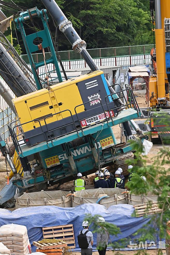 [용인=뉴시스] 김종택 기자 = 지난 5일 경기 용인시 기흥구 서천동 인덕원~동탄 복선전철 공사 현장에서 중장비인 천공기(지반을 뚫는 건설기계)가 15층 높이 아파트 벽면으로 넘어진 사고가 발생했다.6일 오전 소방대원등 관계자들이 장비 등을 투입해 통제선을 설치하고 수습 작업을 하고 있다. 2025.06.06. jtk@newsis.com