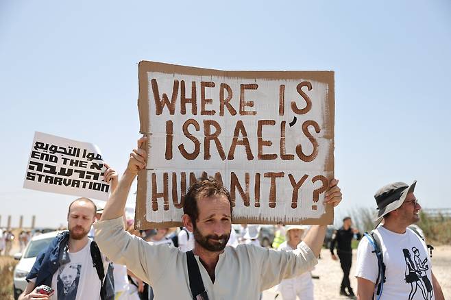 6일 이스라엘 활동가들이 종전을 촉구하며 벌인 사위에서 참가자들이 "이스라엘의 인간성은 어디 있나" "기근을 멈춰라" 등 문구를 적은 피켓을 들고 있다. /EPA 연합뉴스