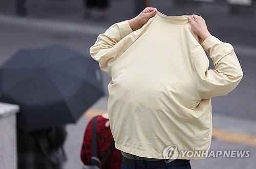 소나기가 내린 지난 2일 서울 서울역 인근에서 한 시민이 옷으로 비를 피하고 있다. [연합뉴스]