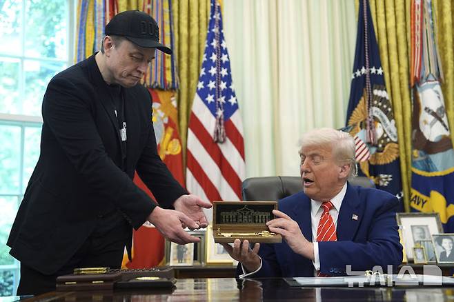 [워싱턴=AP/뉴시스] 지난달 30일(현지 시간) 도널드 트럼프 미국 대통령(오른쪽)이 백악관 집무실에서 정부효율부(DOGE) 수장에서 물러난 일론 머스크 테슬라 최고경영자(CEO)에게 황금 열쇠를 선물하고 있다. 2025.06.07.