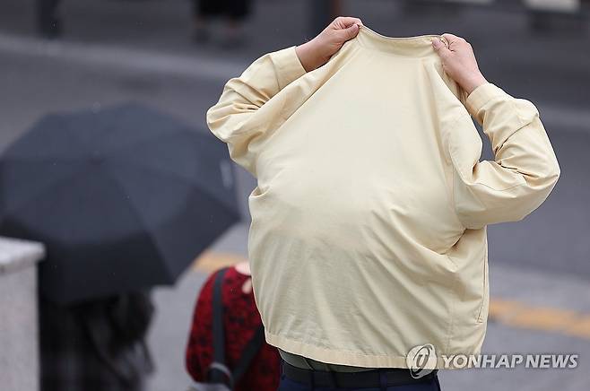 한 시민이 옷으로 비를 막고 있다. [연합뉴스 자료사진]