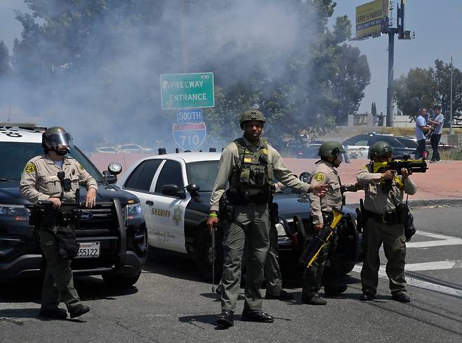 7일(현지 시각( 캘리포니아주 파라마운트의 한 고속도로에서 ICE 및 이민단속 단속을 반대하는 항의 시위대가 로스앤젤레스 카운티 보안관과 대치하고 있다. /연합뉴스