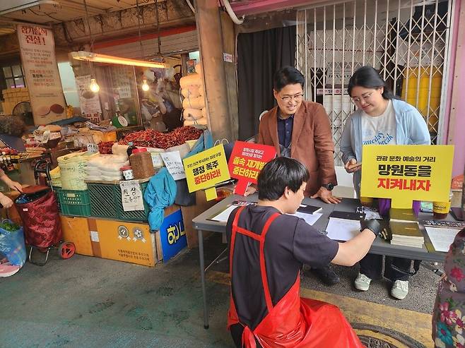 지난 7일 서울 마포구 망원시장에서 김진철 망원동 재개발 저지 공동대책위원회 공동대표(왼쪽)가 재개발 반대 서명을 받고 있다. 허윤희 기자
