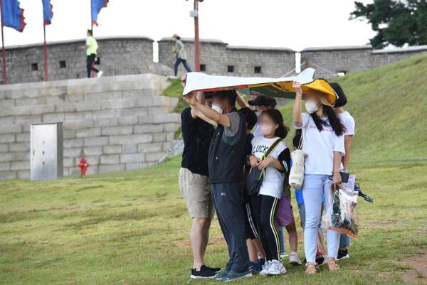 수원화성 창용문을 찾은 시민들이 갑작스럽게 쏟아진 소나기를 피하고 있다. 경기일보DB