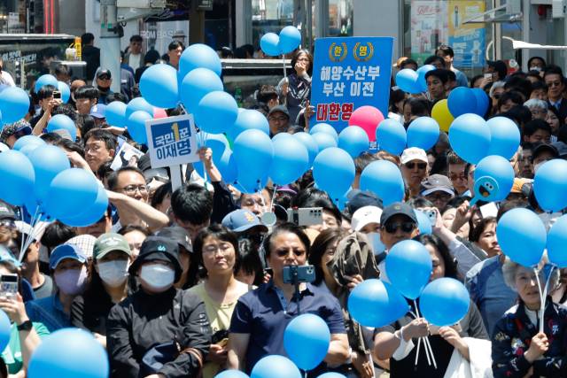 지난 14일 부산 부산진구 서면 젊음의 거리에서 한 지지자가 더불어민주당 이재명 대선 후보의 유세를 지켜보며 "해양수산부 부산 이전 대환영"이라고 적힌 피켓을 들고 있다. 연합뉴스