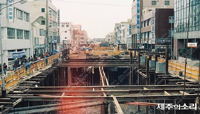 1987년 3월 제주시 동문로에서 관덕로로 이어지는 중앙지하상가 2단계 터파기 공사가 진행 중인 모습. 우측에 조일약국, 좌측에 옛 국민은행(현 다이소) 건물이 보인다. [사진출처-제주시 사진DB]
