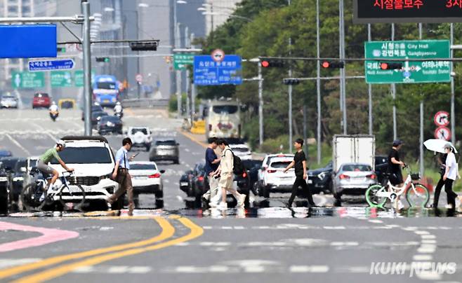 내륙을 중심으로 낮 기온이 30도에 육박한 9일 서울 여의도에서 시민들이 한낮 강한 태양 빛으로 달궈져 아지랑이가 피어오르는 도로를 횡단하고 있다.