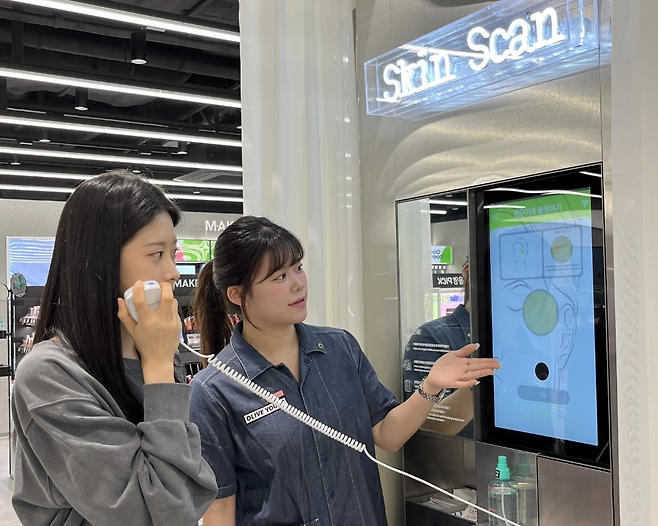 올리브영 매장을 찾은 고객이 직원의 안내를 받아 피부 측정 서비스인 ‘스킨스캔’을 받고 있다.  [CJ올리브영 제공]