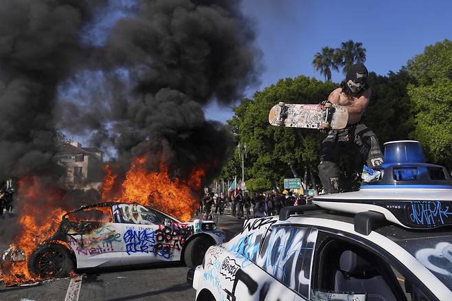 미국 로스앤젤레스(LA)에 이민 단속으로 인한 시위가 거세지면서 8일(현지시간) LA 시내 대도시 구치소 근처에서 한 차량이 화염에 휩싸여있다. [AP]
