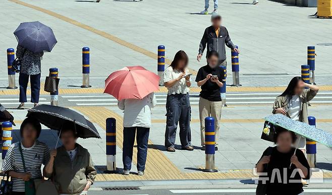 [부산=뉴시스] 하경민 기자 = 무더운 날씨를 보인 4일 부산 동구 부산역 광장 횡단보도에서 시민들이 양산을 쓰고 길을 건너고 있다. 2025.06.04. yulnetphoto@newsis.com