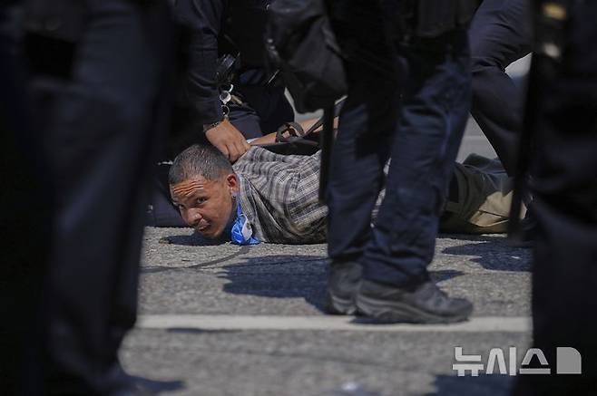 [로스앤젤레스=AP/뉴시스] 8일(현지 시간) 미 캘리포니아주 로스앤젤레스 도심에서 이민세관단속국(ICE)의 불법 이민자 단속 및 체포에 항의하던 시위 참가자가 경찰에 체포되고 있다. 도널드 트럼프 대통령은 불법 이민자 단속에 항의하는 시위에 참여하는 사람들은 마스크를 착용해서는 안 된다고 밝혔다. 2025.06.09.