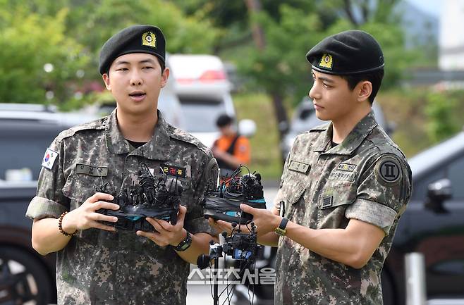 방탄소년단(BTS)의 RM(왼쪽, 김남준)과 뷔(김태형)가 10일 강원도 춘천시 신북읍 체육공원에서 진행된 전역 행사에서 소감을 밝히고 있다. RM은 육군 제15보병사단 군악대에서, 뷔는 2군단 군사경찰 특수임무대에서 1년 6개월 동안 군복무를 했다. 2025. 6. 10.  춘천 | 박진업 기자 upandup@sportsseoul.com