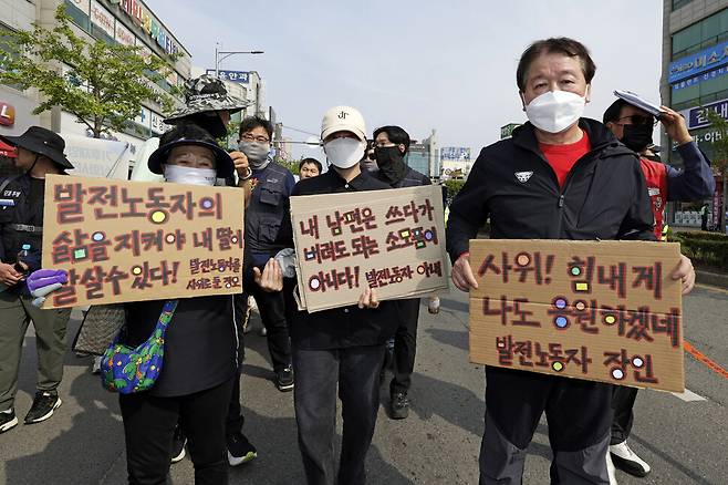한 석탄발전소 노동자 가족이 발전노동자들의 고용 보장을 요구하는 손팻말을 들고 행진하고 있다.