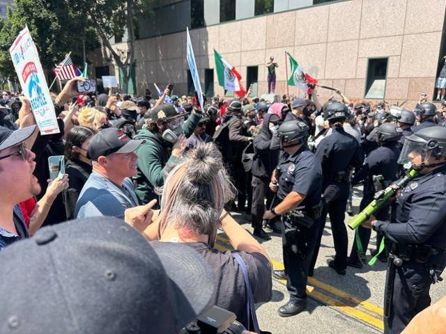 8일 미국 캘리포니아주 로스앤젤레스 메트로폴리탄 구금센터 앞에서 비살상탄 발사기와 곤봉 등을 든 무장 경찰들과 시위대가 대치하고 있다. 로스앤젤레스=이서희 특파원