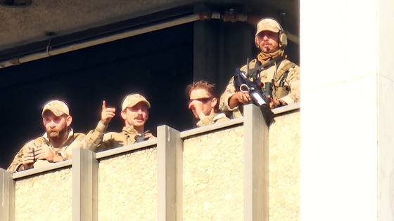 9일(현지시간) 미국 캘리포니아 로스앤젤레스(LA) 다운타운에 위치한 연방 건물 앞에서 트럼프 행정부의 불법 이민자 추방 정책에 반대하는 집회에서 시위대가 '비저항' 제스처를 밝히며 당국의 진압에 맞서자, 건물 고층에서 상황을 지켜보던 지휘부가 대화를 나누고 있다. 로스앤젤레스=강태화 특파원