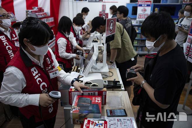 [도쿄=AP/뉴시스] 5일(현지 시간) 일본 도쿄의 한 전자제품 판매점에서 한 손님이 닌텐도의 차세대 콘솔 ‘스위치2’를 구매하고 있다. 이날 공식 출시된 ‘스위치2’는 전작과 많은 유사점을 지니면서도, 더 커진 화면과 향상된 그래픽을 갖춘 것이 특징이다. 2025.06.05.