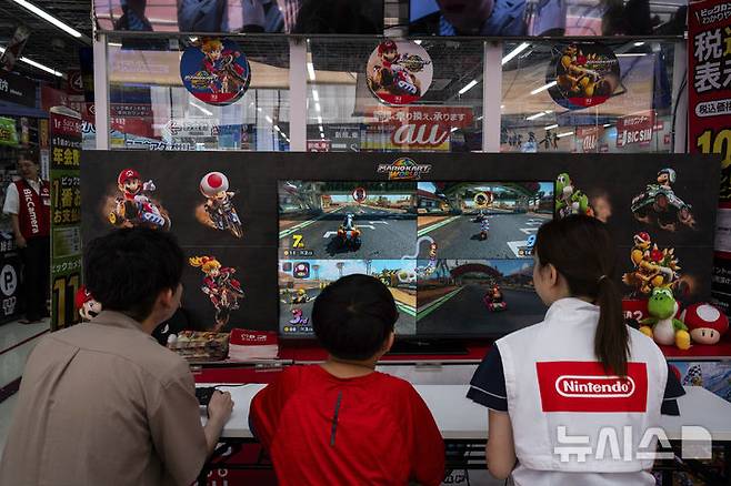 [도쿄=AP/뉴시스] 5일(현지 시간) 일본 도쿄의 한 전자제품 판매점에서 어린이들과 이곳 직원이 닌텐도의 차세대 콘솔 ‘스위치2’를 체험하고 있다. 이날 공식 출시된 ‘스위치2’는 전작과 많은 유사점을 지니면서도, 더 커진 화면과 향상된 그래픽을 갖춘 것이 특징이다. 2025.06.05.