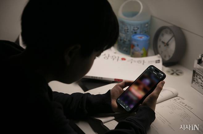 책상 앞에 앉아서 스마트폰을 조작하는 아동의 모습.ⓒ시사IN 이명익