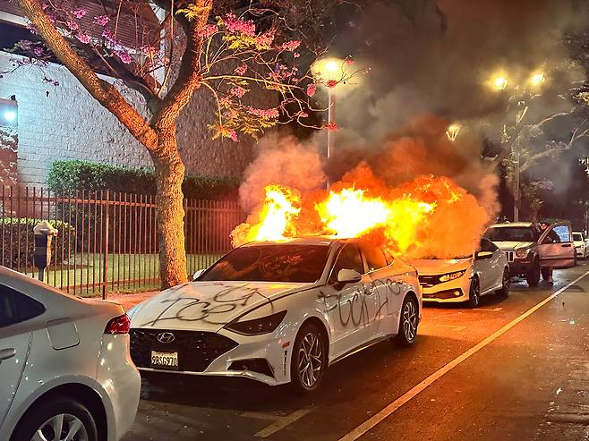 9일 오후 11시(현지 시각) 미국 로스앤젤레스(LA) 시내에 주차된 차량들이 불길에 휩싸여 있다. 한 자동차엔 ‘망할 ICE(이민세관단속국)’라는 스프레이 낙서도 보인다. 도널드 트럼프 행정부의 불법 이주자 단속·추방에 항의하는 대규모 시위 나흘째인 이날, 트럼프는 주 방위군에 이어 해병대도 진압에 투입하라고 명령했다. /오로라 특파원