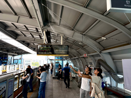 대구교통공사가 지상에 위치한 도시철도 3호선의 구조적 특성을 고려해 승강장 환경 개선에 박차를 가하고 있다. 사진은 만평역 승강장 쿨링 포그(Cooling Fog) 쐬는 이용객 모습. 대구교통공사 제공