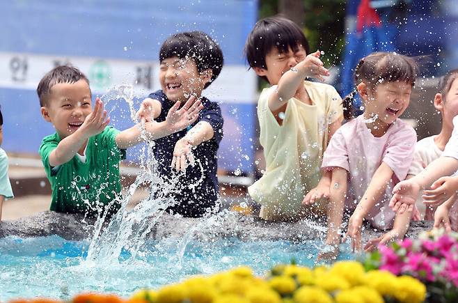 무더운 날씨가 이어지는 지난 10일 광주 북구청 광장으로 야외활동을 나온 북구청직장어린이집 아이들이 물레방아에서 물장구를 치며 더위를 식히고 있다. 연합뉴스