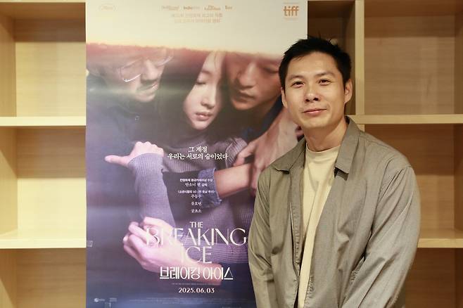 지난달 30일 서울 마포구 한 카페에서 안소니 첸 감독이 <브레이킹 아이스> 포스터 앞에 서 있다. 찬란 제공