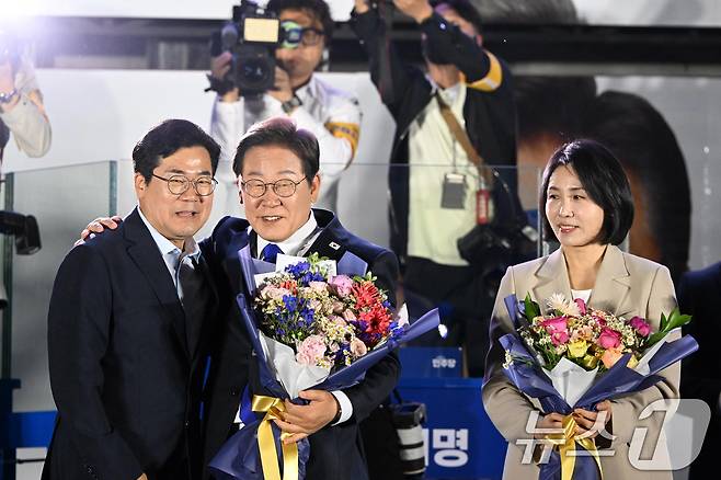 당선이 확실시된 이재명 더불어민주당 대통령 후보가 김혜경 여사와 4일 오전 서울 여의도 국회 앞을 찾아 박찬대 상임총괄선대본부장으로부터 꽃다발을 받고 있다. (공동취재) 2025.6.4/뉴스1 ⓒ News1 안은나 기자