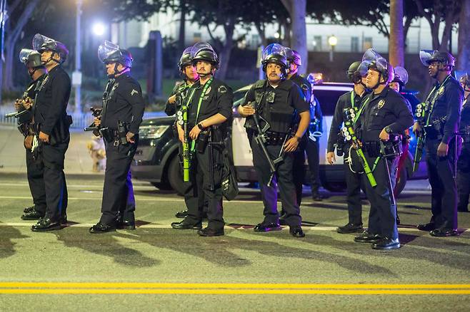 10일 로스앤젤레스에서 연방 이민법 위반에 대한 항의 시위가 며칠간 이어진 후 통금령이 발령되자 진압 장비를 착용한 경찰관들이 시청 근처에 대열을 이루고 있다. /연합뉴스