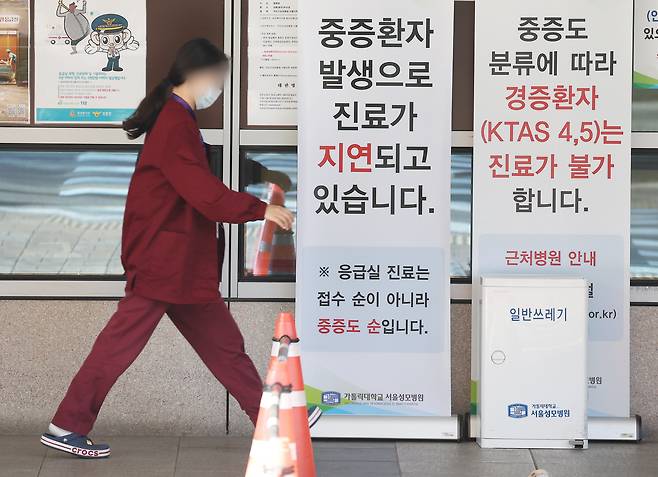 서울 시내 한 대형병원 응급실 앞에서 한 직원이 중증환자 발생으로 진료가 지연되고 있다는 안내문을 치우고 있다. /연합뉴스