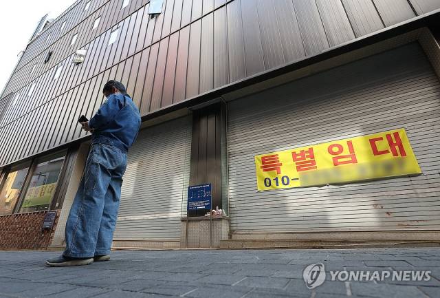 최근 ‘특별임대’ 현수막이 붙은 건물 앞에서 한 행인이 휴대폰을 들여다보고 있다. 연합뉴스