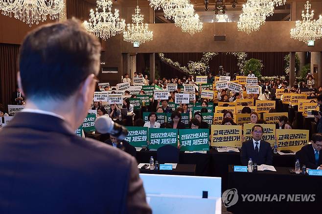 간호법 관련 진료지원업부 제도화 공청회장 피케팅 (서울=연합뉴스) 신현우 기자 = 박민수 보건복지부 제2차관이 21일 서울 용산구 피크앤파크 컨벤션 로얄홀에서 열린 간호법 제정에 따른 진료지원업무 제도화 방안 공청회에 참석해 개회사하는 가운데 대한간호협회 회원과 전국민주노동조합총연맹 공공운수노조 의료연대본부 조합원이 각각 피케팅하고 있다. 2025.5.21 nowwego@yna.co.kr