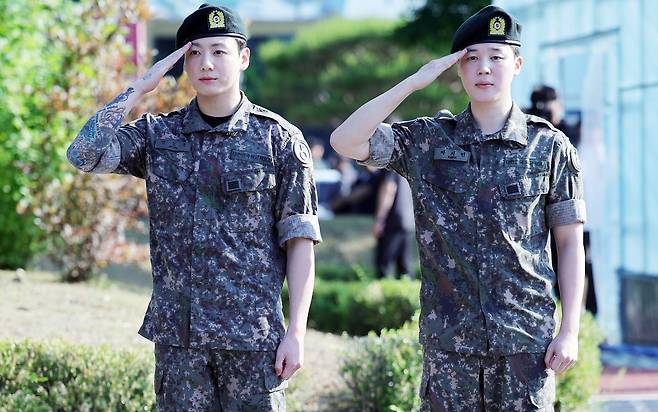 육군 현역 복무를 마친 그룹 방탄소년단(BTS)의 지민(오른쪽)과 정국이 지난 11일 오전 경기 연천군 연천공설운동장에서 거수경례로 전역을 알리고 있다.  [연합]