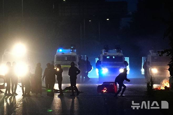 [포터다운( 영 북아일랜드)=AP/뉴시스] 북아일랜드 포터다운에서 폭동혐의로 단속된 복면한 청소년들이 6월 12일 경찰 트럭 옆에대기하고 있다. 이들은 14세 소년 2명의 성폭력 재판에 항의하며 사흘 연속 야간에 차량 방화와 투석전 등 소동을 벌였다. 2025. 06.13.