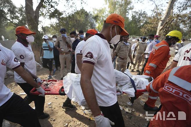 [아마다바드=AP/뉴시스] 12일(현지 시간) 인도 구자라트주 아마다바드 여객기 추락 현장에서 구조대가 희생자 시신을 옮기고 있다. 이날 아마다바드 공항에서 이륙한 영국행 에어인디아 AI171편 여객기가 추락해 탑승자 242명 가운데 1명을 제외한 전원이 숨졌으며, 추락 현장의 학생 등 약 50명도 사망한 것으로 전해졌다. 2025.06.13.
