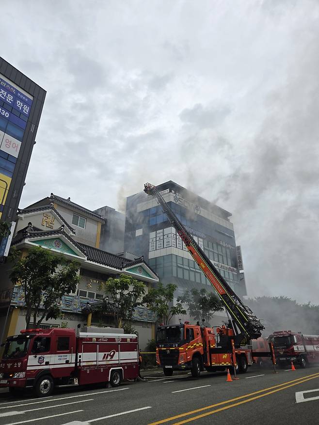 13일 부산 기장군 정관읍 한 상가건물에서 화재가 발생하자 소방대원들이 고가사다리차량을 동원해 진화하고 있다. 부산소방재난본부 제공